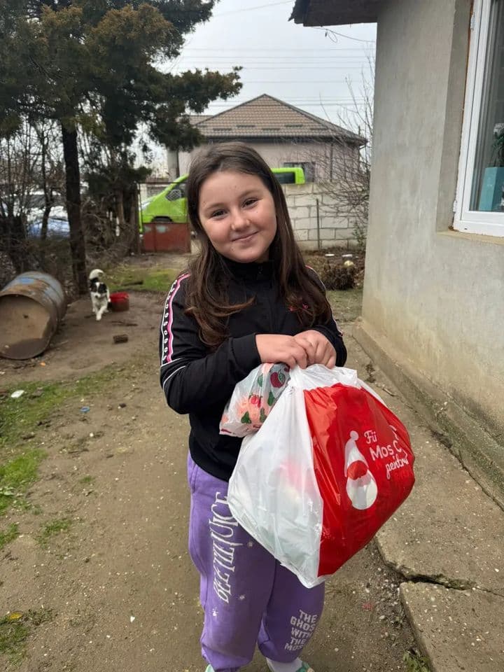 Fetiță zâmbind, cu punga de cadouri a campaniei