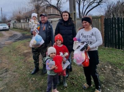 O familie cu patru copii pe uliță, fiecare cu câte o pungă de cadouri în mână