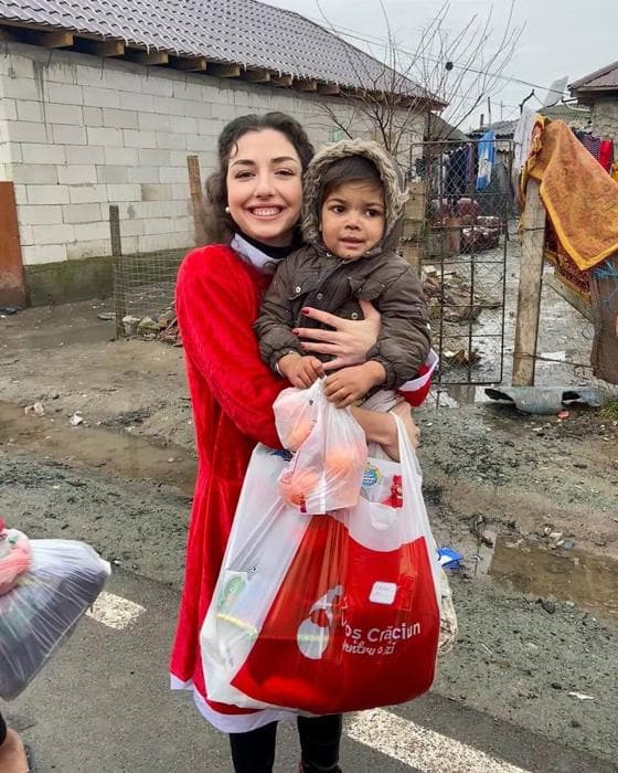 Voluntară Moș Crăciun ținând în brațe un copil cu un cadou