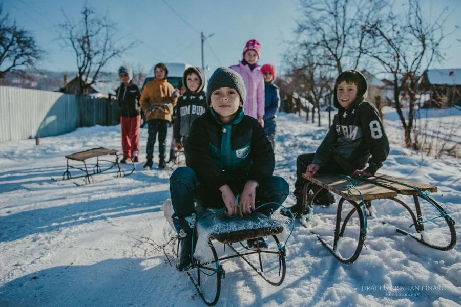 Copii pe sănii, în zăpadă, într-un sat
