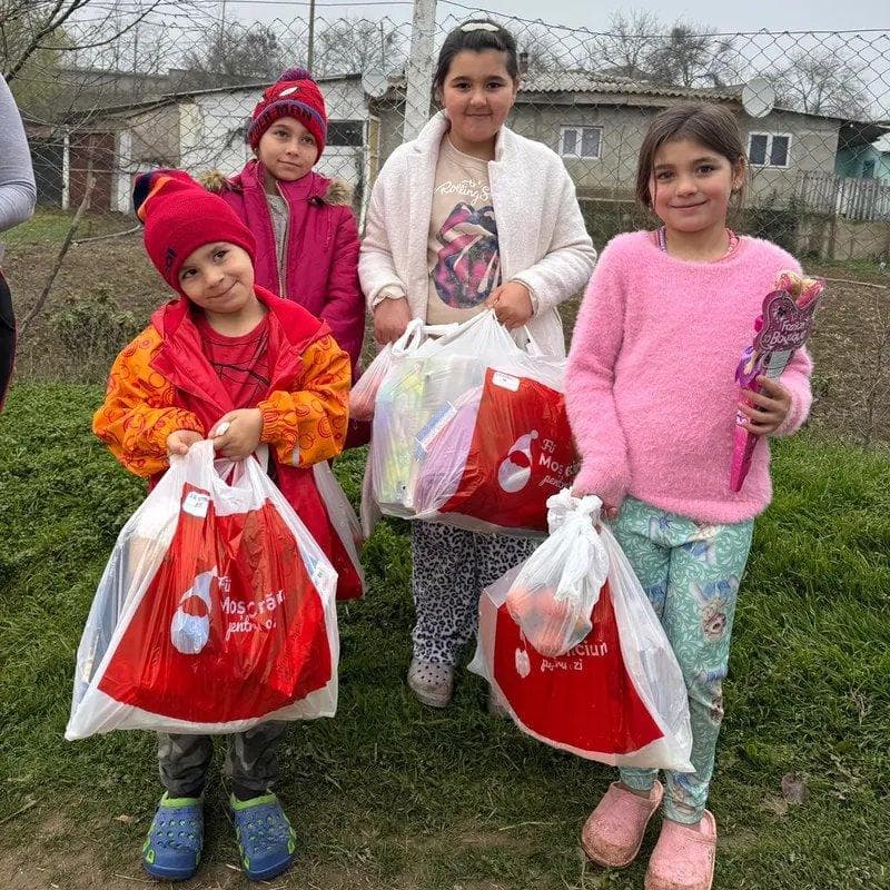 Copii cu pungile de cadouri primite de la caravana Fii Moș Crăciun pentru o zi